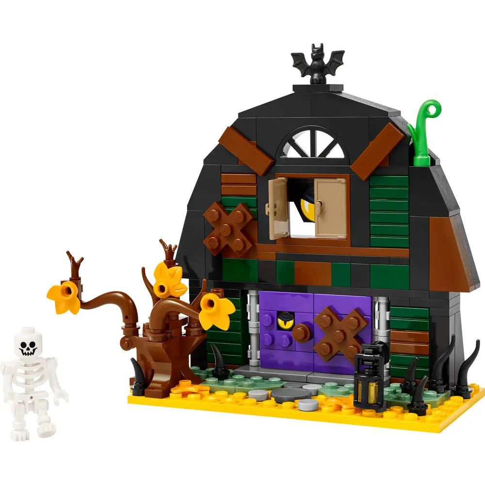 Assembled LEGO Halloween Barn set features a black and green barn with boarded windows, a twisted tree with yellow flowers, a skeleton minifigure, and eerie details like a bat, lantern, and peeking eyes.