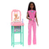 Barbie Baby Doctor brunette doll stands beside pink and teal nursery station holding baby doll, wearing stethoscope and scrubs, ready to care for her little patient.