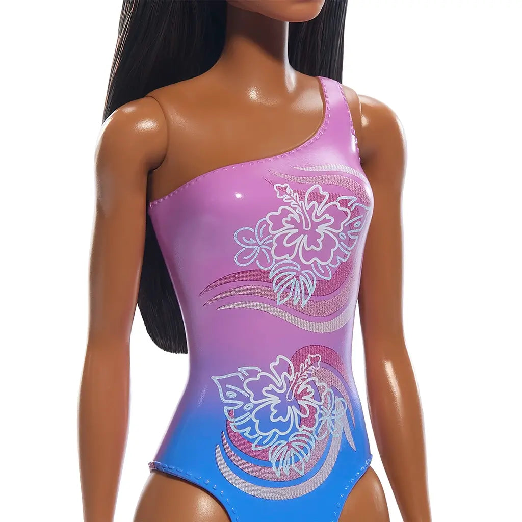 Detailed close-up of Barbie doll’s purple-to-blue gradient swimsuit featuring shiny material with two large hibiscus flower prints and flowing wave-like patterns.