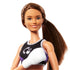 Close-up of Barbie boxer doll with long brown hair in ponytail, wearing black sports crop top with logo and white boxing gloves, smiling confidently.