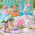Calico Critters Blooming Baby Friends toys displayed in a pastel garden scene with miniature animal figures dressed in floral outfits surrounded by colorful flowers and clouds