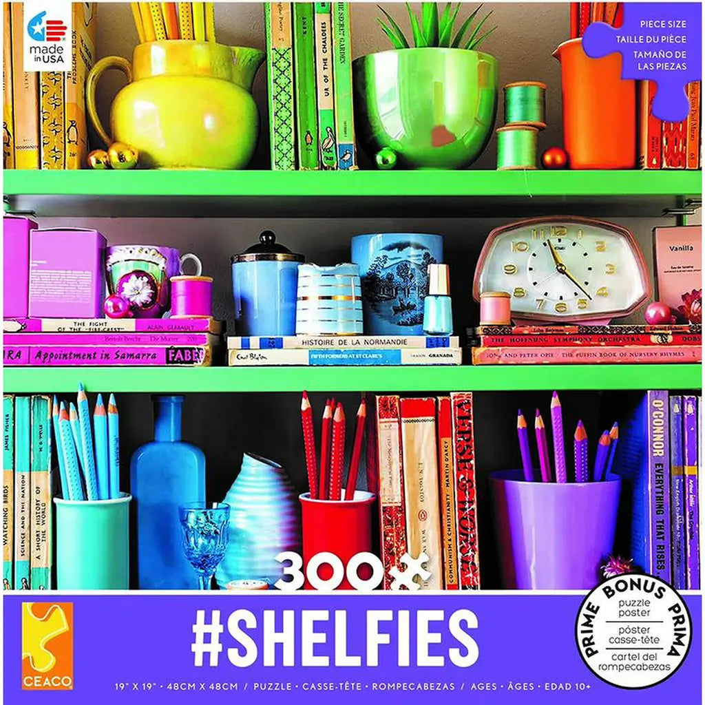 Ceaco #Shelfies 300-piece puzzle box featuring a vibrant bookshelf with colorful books, jars, pencils, and decorative vases arranged by color, blending bright greens, blues, reds, and purples.