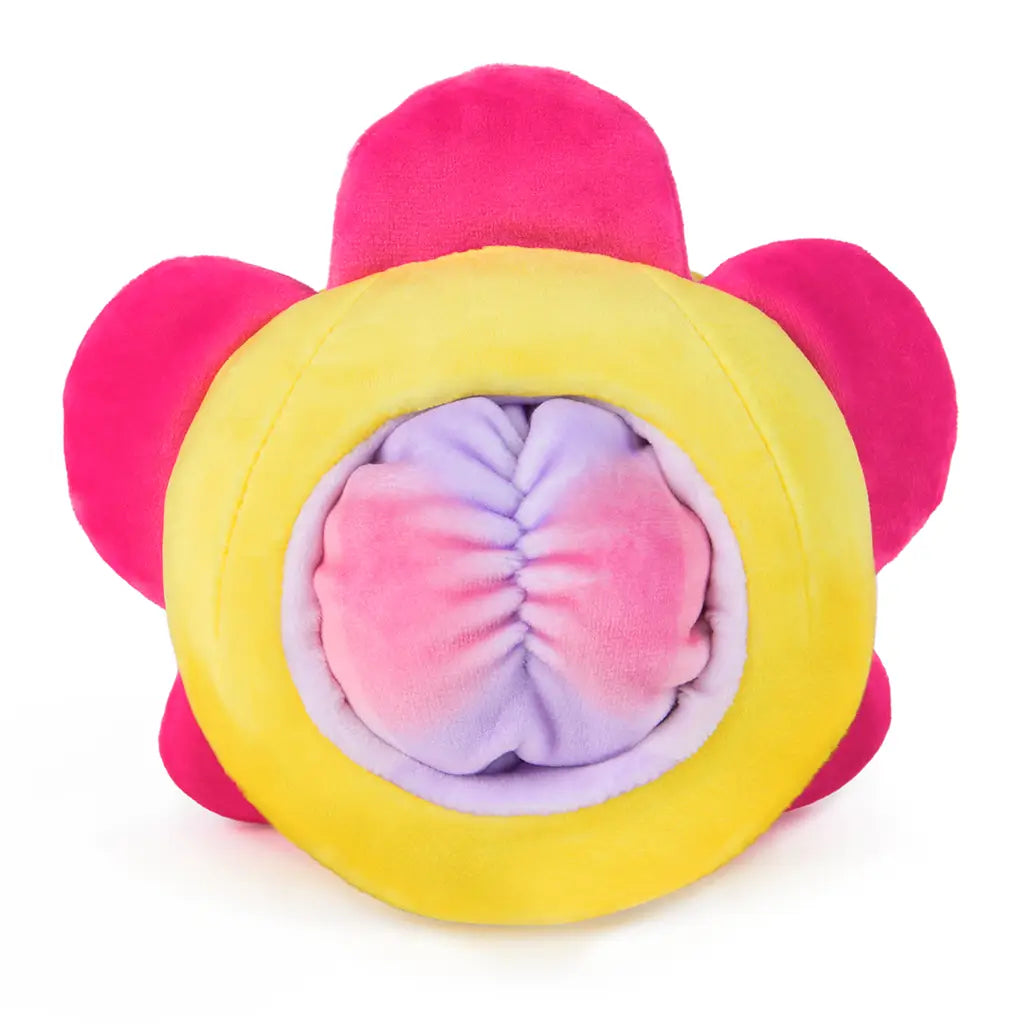Rear view of a reversible plush flower toy showing pastel purple and pink cinched fabric resembling a cheeky bottom, framed by a bright yellow and pink outer flower body.