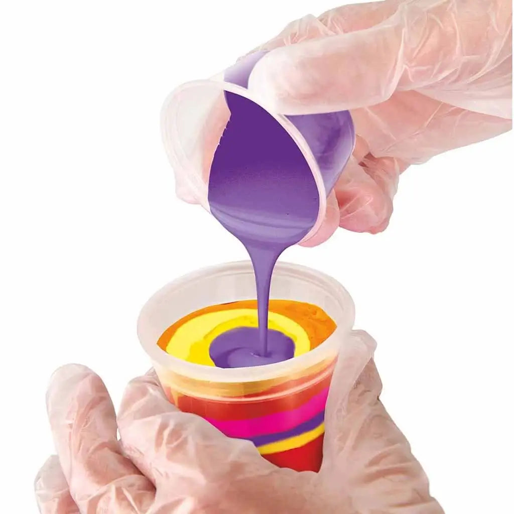 Close-up of gloved hands pouring purple paint into a cup layered with yellow, orange, and pink paints, creating a vivid swirl effect ideal for acrylic pour art projects.