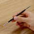 Black double-tipped paintbrush with fine orange bristles held in hand, designed for precise acrylic painting on wood or canvas surfaces, ideal for paint by numbers kits.
