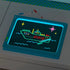 Discovery Glow Easel LED light drawing board lying flat on a desk, glowing neon artwork of a ship and stars, with blue and red markers placed nearby under dim lighting.
