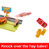 Disney Pixar Cars toy playset showing Lightning McQueen car midair after racing down track, knocking over bright yellow hay bale obstacles beside Radiator Springs sign.