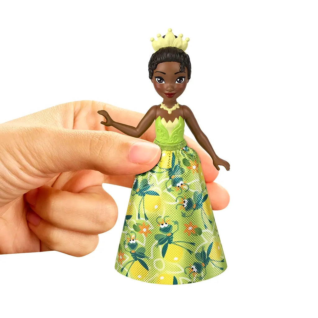 Close-up of Tiana doll with green floral dress and crown, held by a hand, highlighting fine details of the Disney Princess Friends toy.