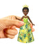Close-up of Tiana doll with green floral dress and crown, held by a hand, highlighting fine details of the Disney Princess Friends toy.