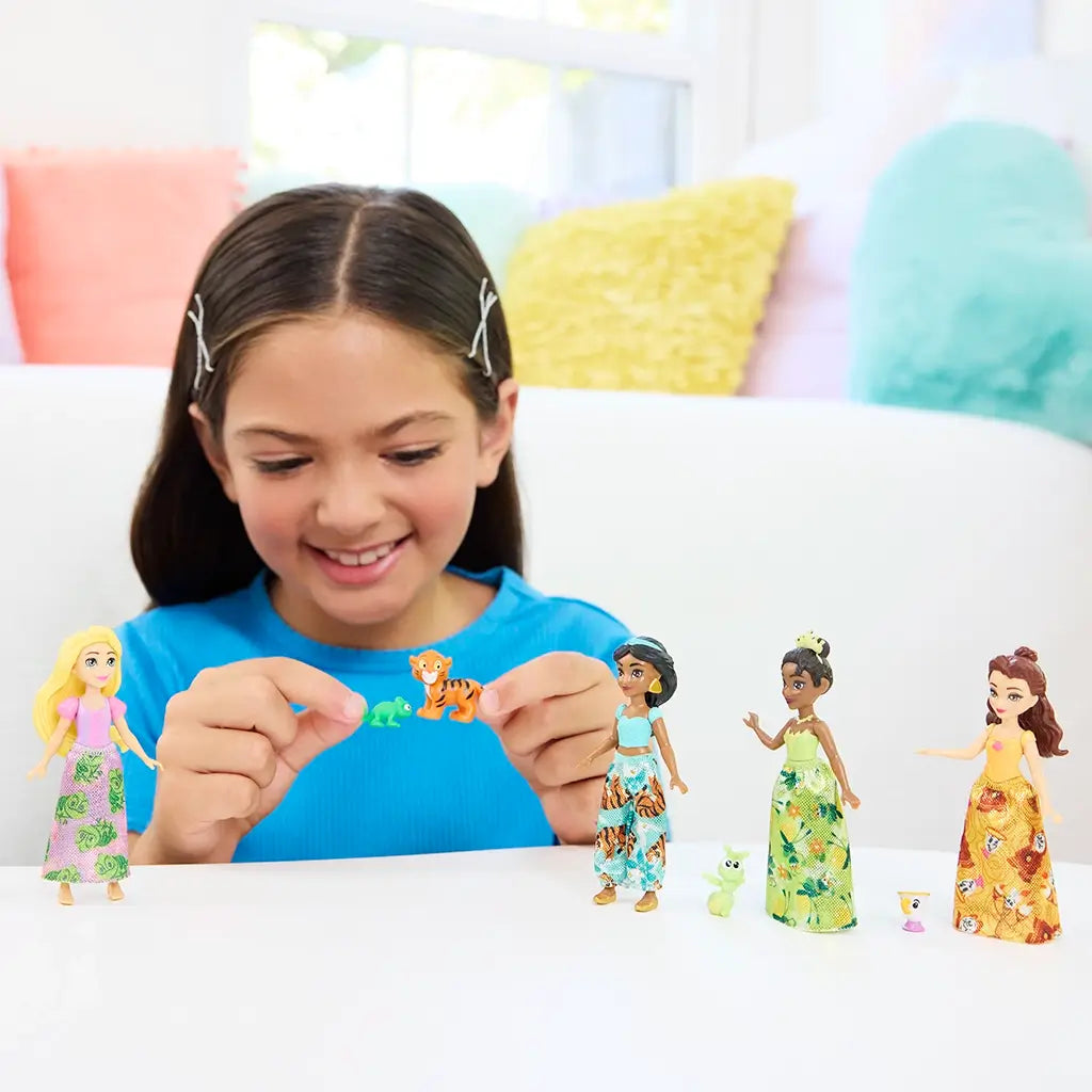 Smiling child in a blue shirt playing with Disney Princess dolls and animal friends, creating an imaginative and inclusive play environment.