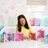 Smiling child in a yellow top playing with multiple Disney Princess Tower Surprise playsets, each castle featuring miniature princess figures like Belle, Snow White, and Ariel on a white play table.