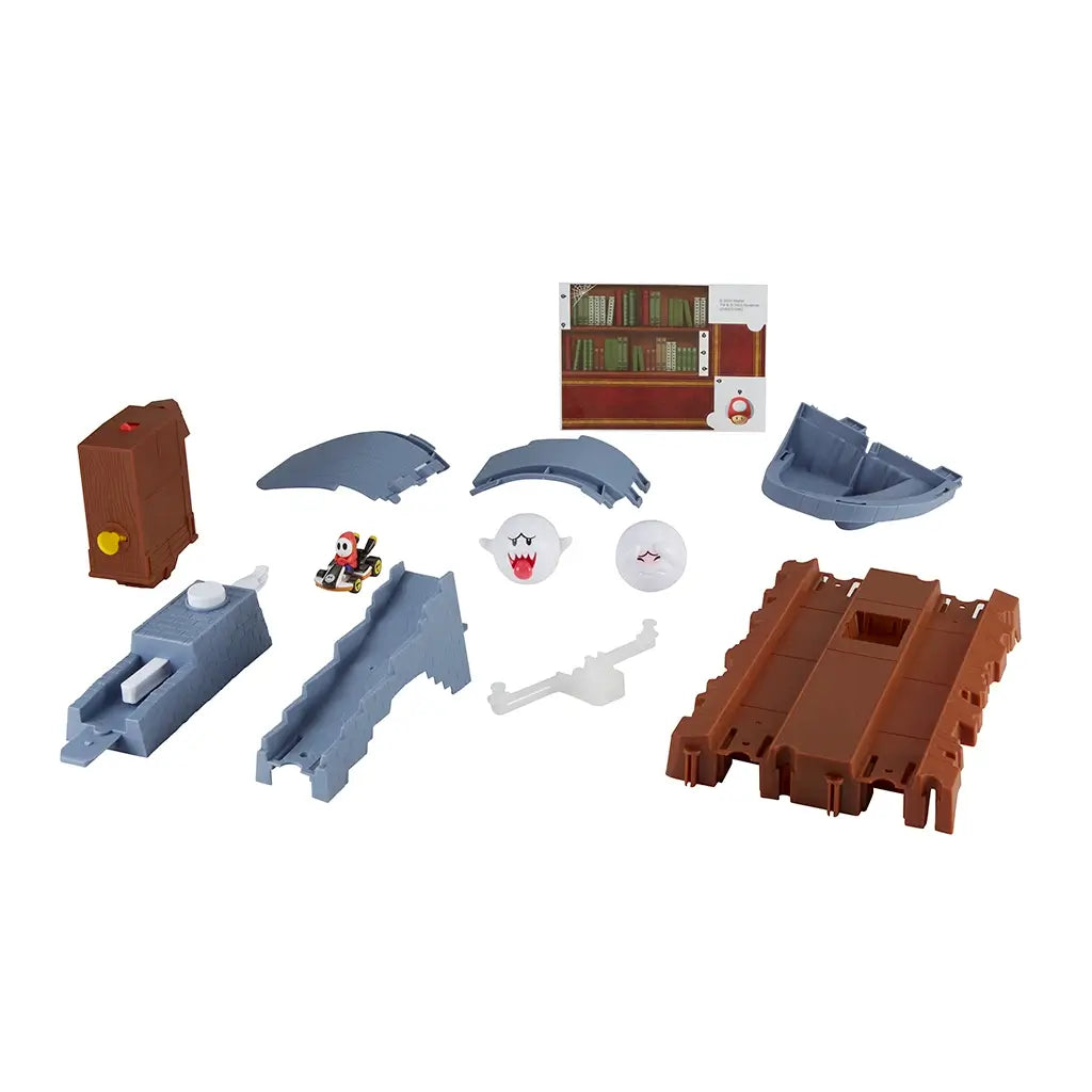 Hot Wheels Mario Kart Boo’s Spooky Sprint set shows unassembled gray track pieces, brown library bookshelf obstacle, two Boo ghost figures, and Shy Guy kart for racing play.