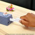 A child’s hand launches a Hot Wheels Mario Kart car from gray stone-look ramp with red mushroom launcher, sending vehicles racing into Boo’s Spooky Sprint haunted track.