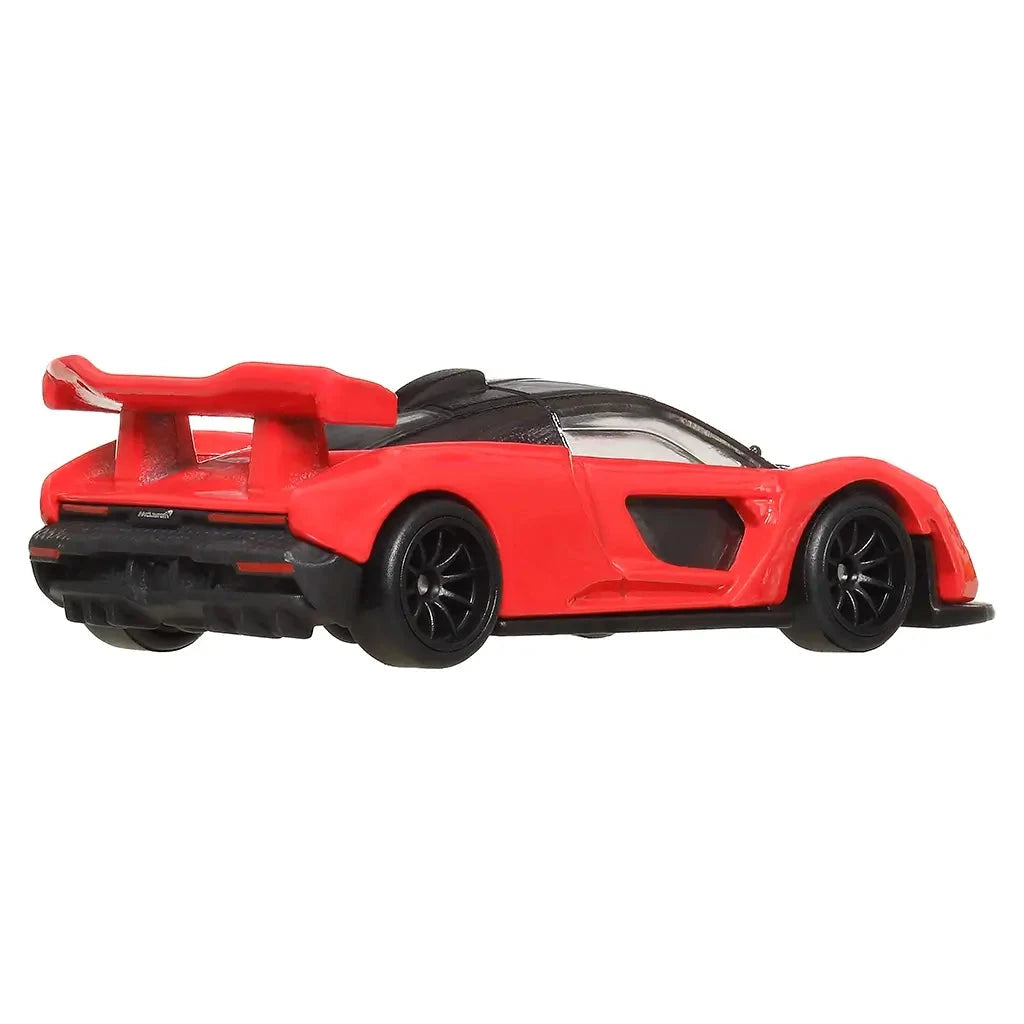 Rear angled view of Hot Wheels McLaren Senna die-cast car in red with black accents, large spoiler, and detailed exhaust area.