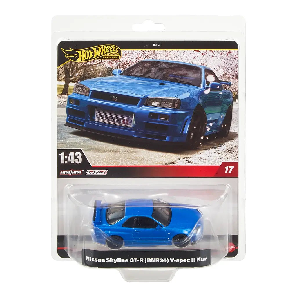 Hot Wheels Premium Nissan Skyline GT-R BNR34 V-spec II Nur diecast in metallic blue with detailed bodywork, packaged in 1:43 scale card featuring cherry blossom street backdrop.