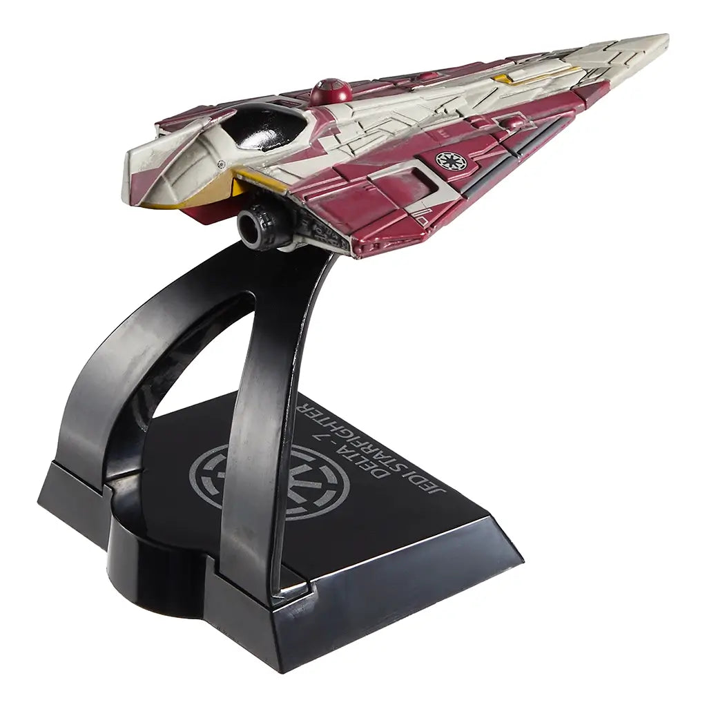 Rear-angled view of Hot Wheels Star Wars Delta-7 Jedi Starfighter toy showing engine detail, pointed tail fins, and a maroon and cream color scheme, resting on a custom stand with silver Galactic Republic emblem.