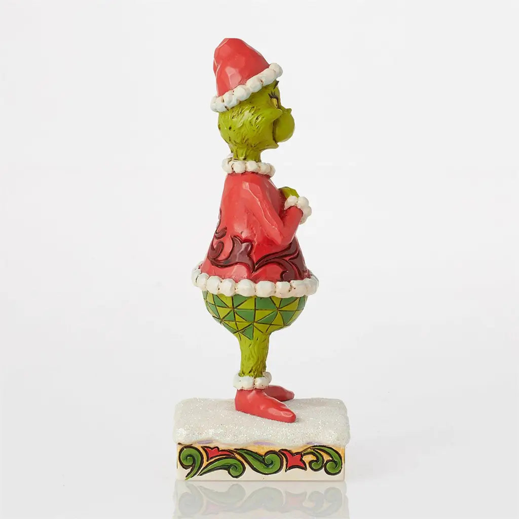 Side view of a 6-inch Jim Shore Grinch figurine wearing a Santa outfit with red coat, green legs, and festive patterns, standing on a decorative base.