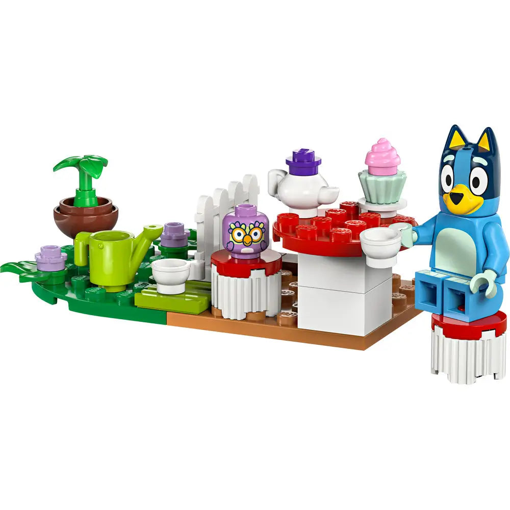 LEGO Bluey Tea Party building set showing Bluey the blue heeler sitting at a red and white table with teacups, a cupcake, and garden plants, built from small interlocking LEGO bricks.