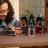 Builder assembling LEGO Wednesday Morticia’s Cottage set, placing detailed gothic furniture inside the open house, with Wednesday and Morticia minifigures nearby.