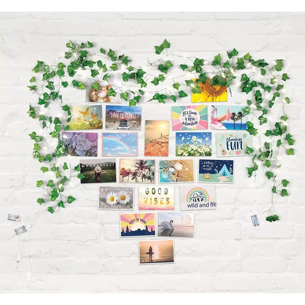 Wall collage of colorful photo cards with faux ivy string lights arranged in a heart shape, creating a cozy, illuminated decor setup on a white brick background.