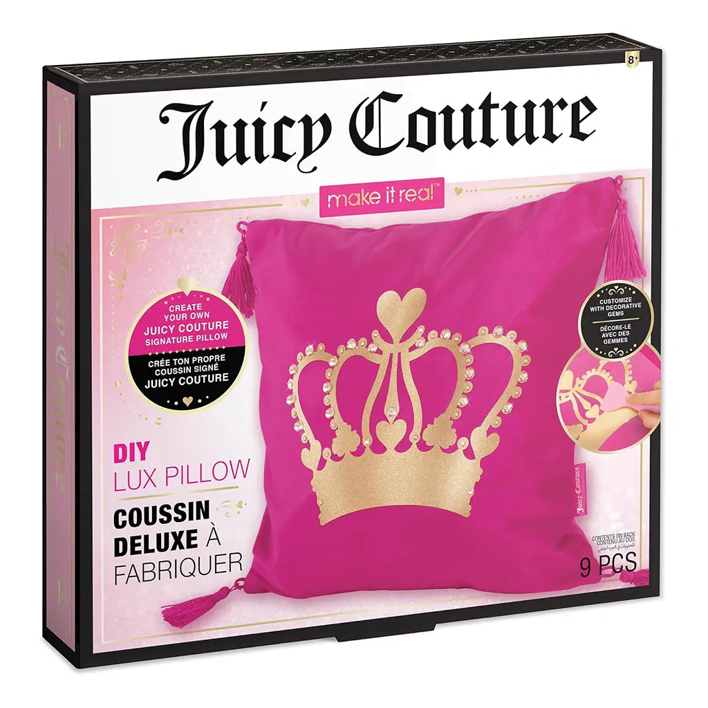 Front of Juicy Couture DIY Lux Pillow Craft Set box showing a bright pink pillow with a gold glitter crown design, tassel corners, and brand logo, part of the Make It Real craft line.