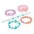 Colorful Linxo celebration-style bracelets made from translucent plastic beads in pastel purple, pink, teal, and orange tones, arranged in flower patterns on a white background, promoting creative jewelry design.
