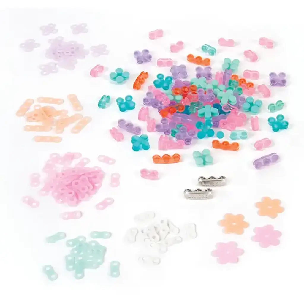 Assorted Linxo jewelry set components in pastel shades of pink, purple, teal, orange, and white plastic pieces shaped like links and flowers, spread on a white surface for bracelet crafting.