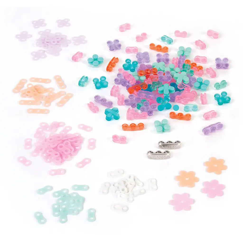 Linxo bracelet-making kit contents on a white surface, including pastel beads, flower-shaped charms, silver connectors, and colorful links for custom seaside-style jewelry.