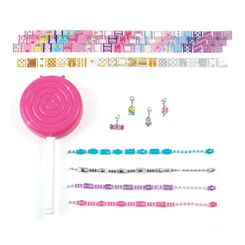 Make It Real Shrink Magic DIY Bracelet Kit contents displayed on white background, featuring candy-themed charms, colorful beads, and lollipop-shaped shrink tool.