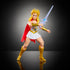 Masters of the Universe She-Ra action figure with long blonde hair, white and gold outfit, red cape, and silver sword, posed in dynamic battle stance on reflective black surface.