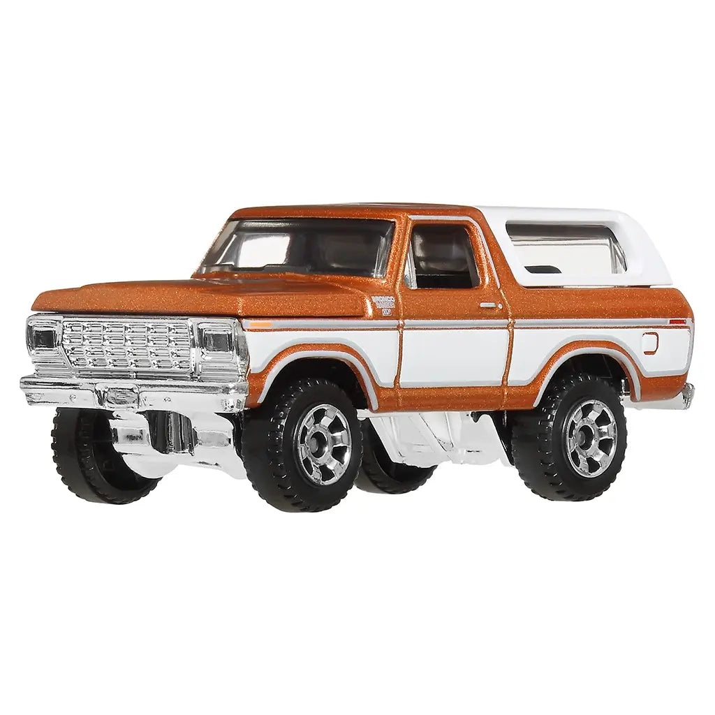 Matchbox 1978 Ford Bronco 1:64 scale toy car in metallic orange and white with chrome grille and raised body, shown from a front angled view highlighting classic SUV styling.