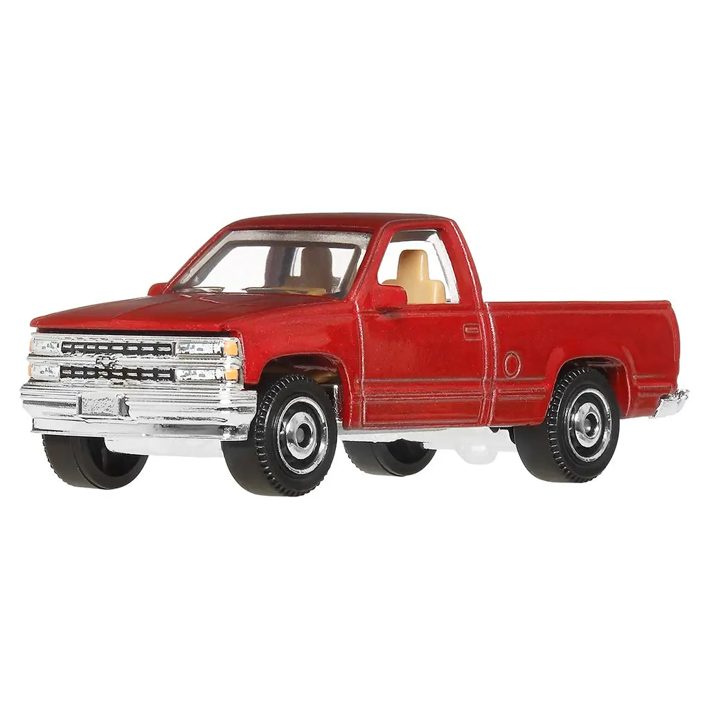 Front angled view of red Matchbox 1995 Chevy C1500 diecast pickup with chrome front grille, tan interior, black wheels, and long bed truck body in 1:64 scale.