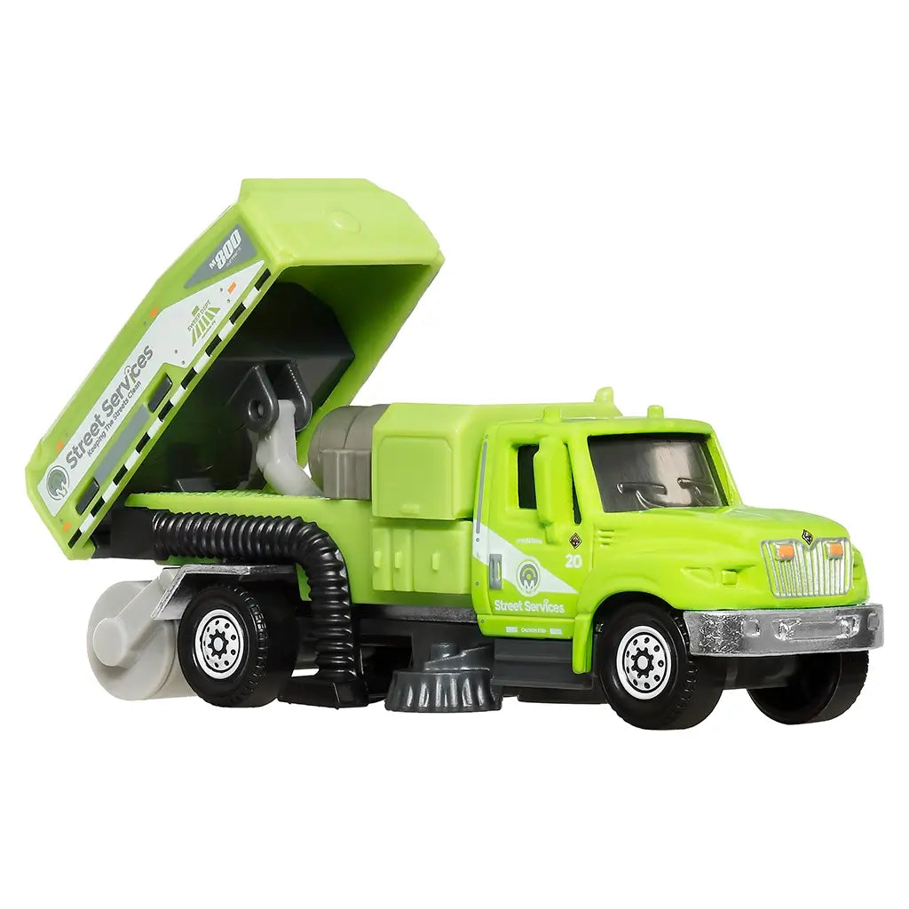 Matchbox International WorkStar street sweeper die-cast toy truck in green with a tilting rear compartment, cleaning brushes, and detailed “Street Services” decals for authentic play action.