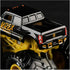 Closeup of Monster Jam Kane Brown K-Rex 1:64 scale diecast truck, featuring glossy black body with orange accents, gold chassis, and oversized rugged black tires.