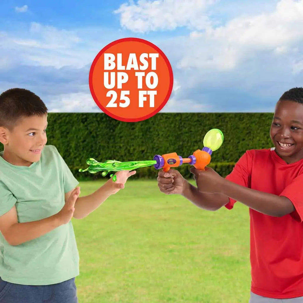 Two smiling kids playing outside with the Nickelodeon Slime Splat Splasher, blasting bright green slime up to 25 feet across a grassy yard under a blue sky.