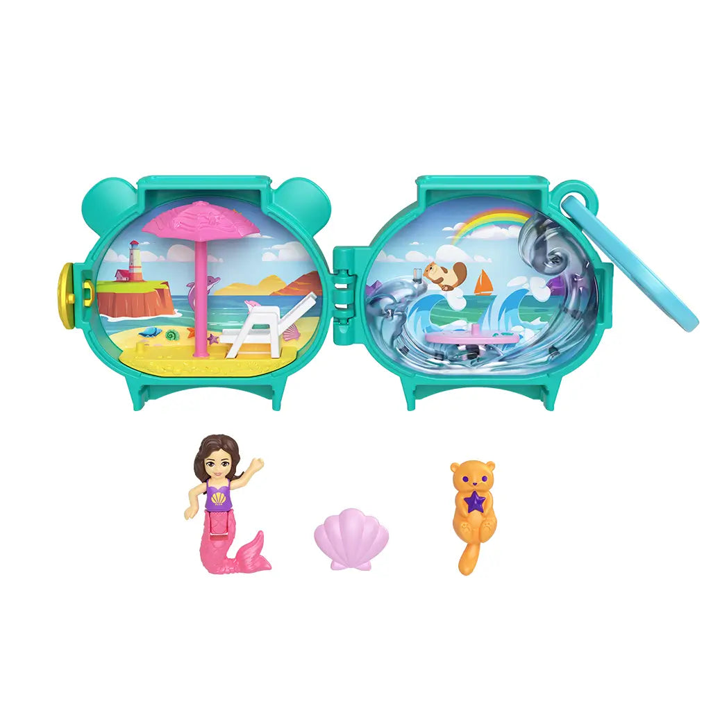 Full Polly Pocket Otter Locket playset opened to display beach scene with mermaid doll and umbrella on one side and surfing otter with rainbow ocean background on the other, plus small accessories.