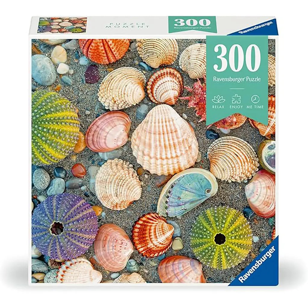 Ravensburger 300-piece Puzzle Moments box featuring colorful seashells and sea urchins on sandy beach pebbles, designed for a relaxing and mindful puzzling experience.