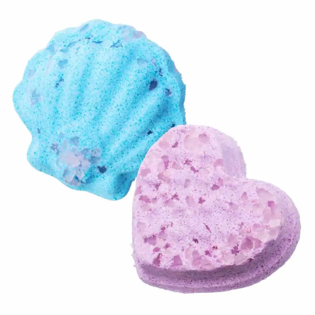Two handmade Real Littles Micro Craft fizz bombs in blue seashell and purple heart shapes with crystal-like texture, showing their detailed bubbly surface and pastel colors for bath fun.