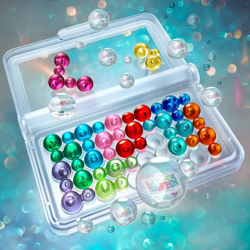 Transparent travel-friendly Smart Games IQ Bubbles case shown open with shiny red, blue, green, and yellow puzzle pieces, displayed against a glowing teal and bubble-filled background.
