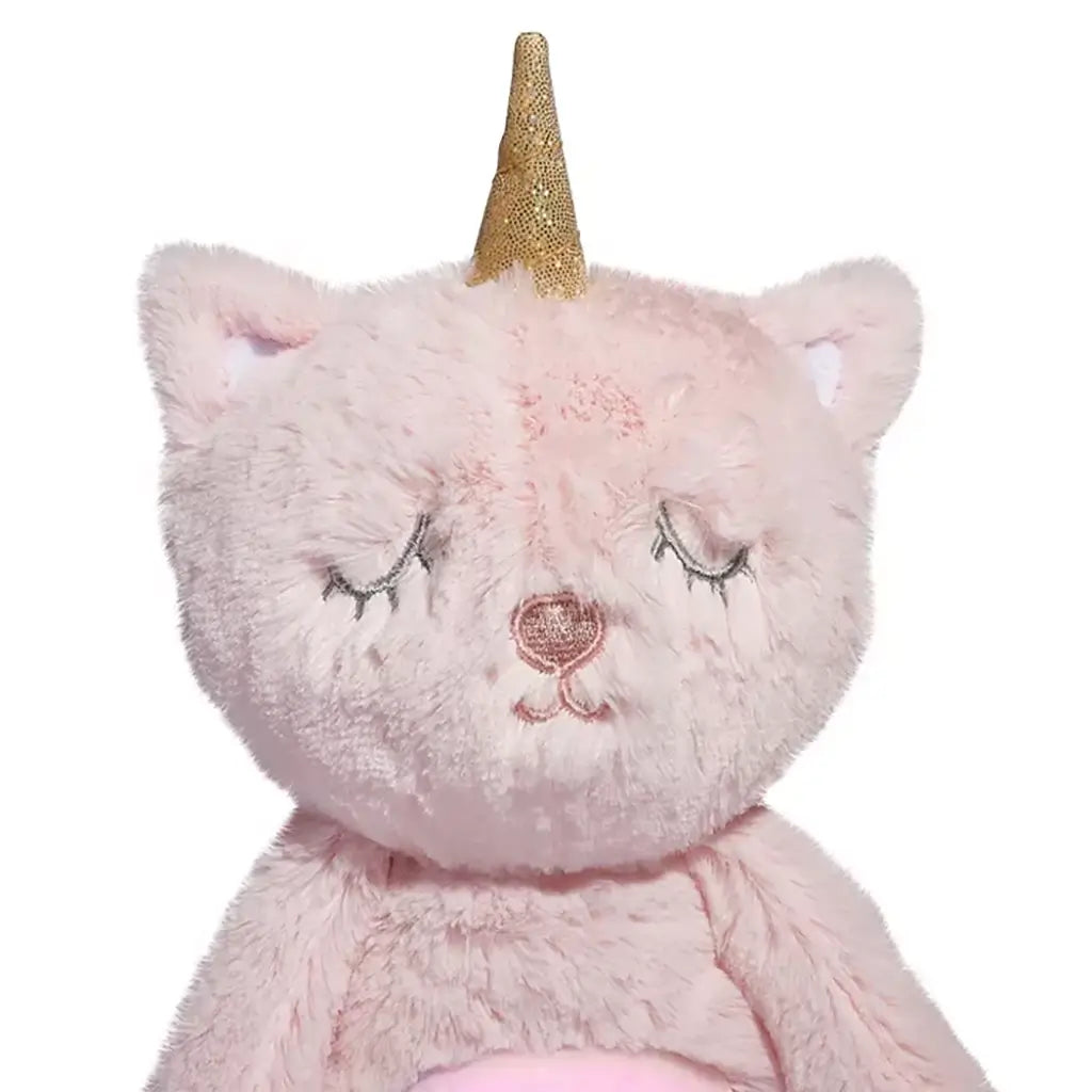 Close-up of plush unicorn cat face showing gold horn, pink fur, and embroidered sleepy eyes and nose, emphasizing soft, cuddly texture.