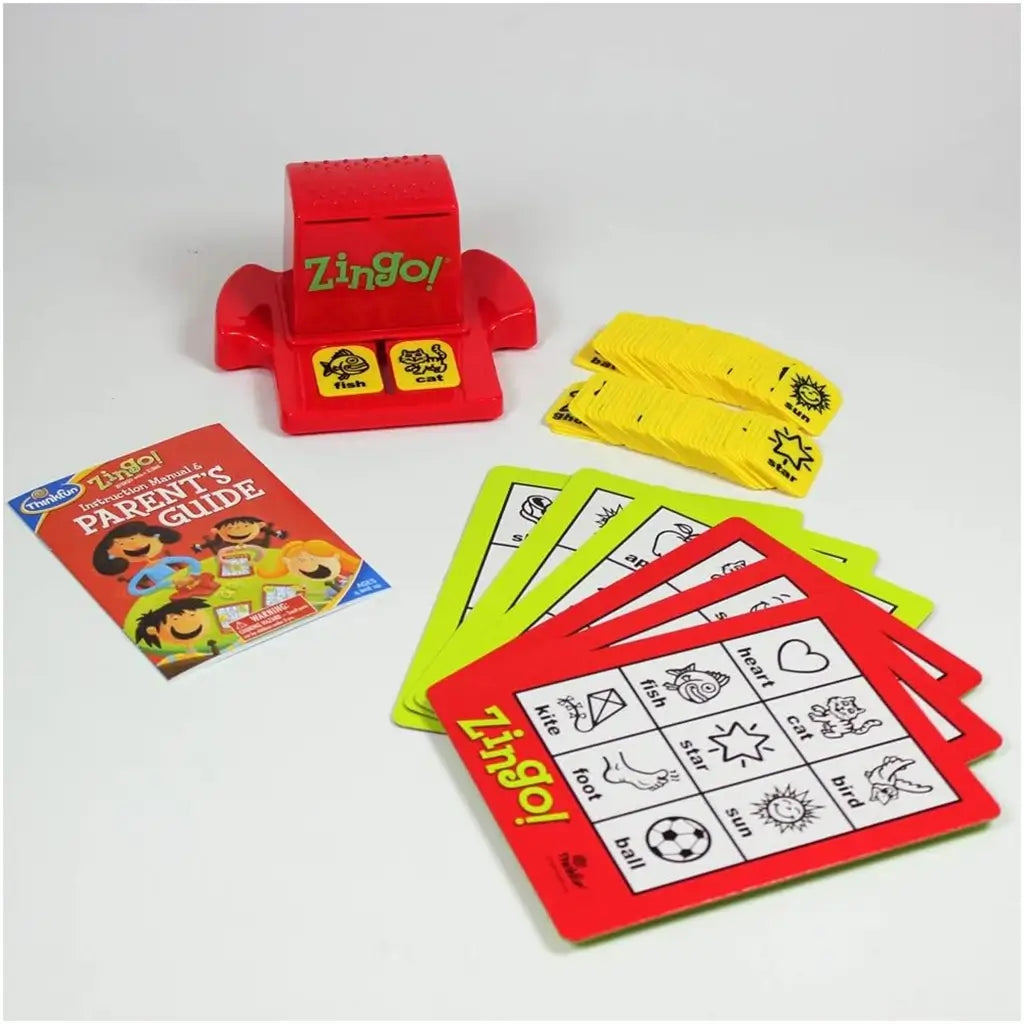 ThinkFun Zingo complete set showing red Zinger dispenser, yellow tiles, colorful player cards, and illustrated parent’s guide, designed to build language, matching, and reading skills.
