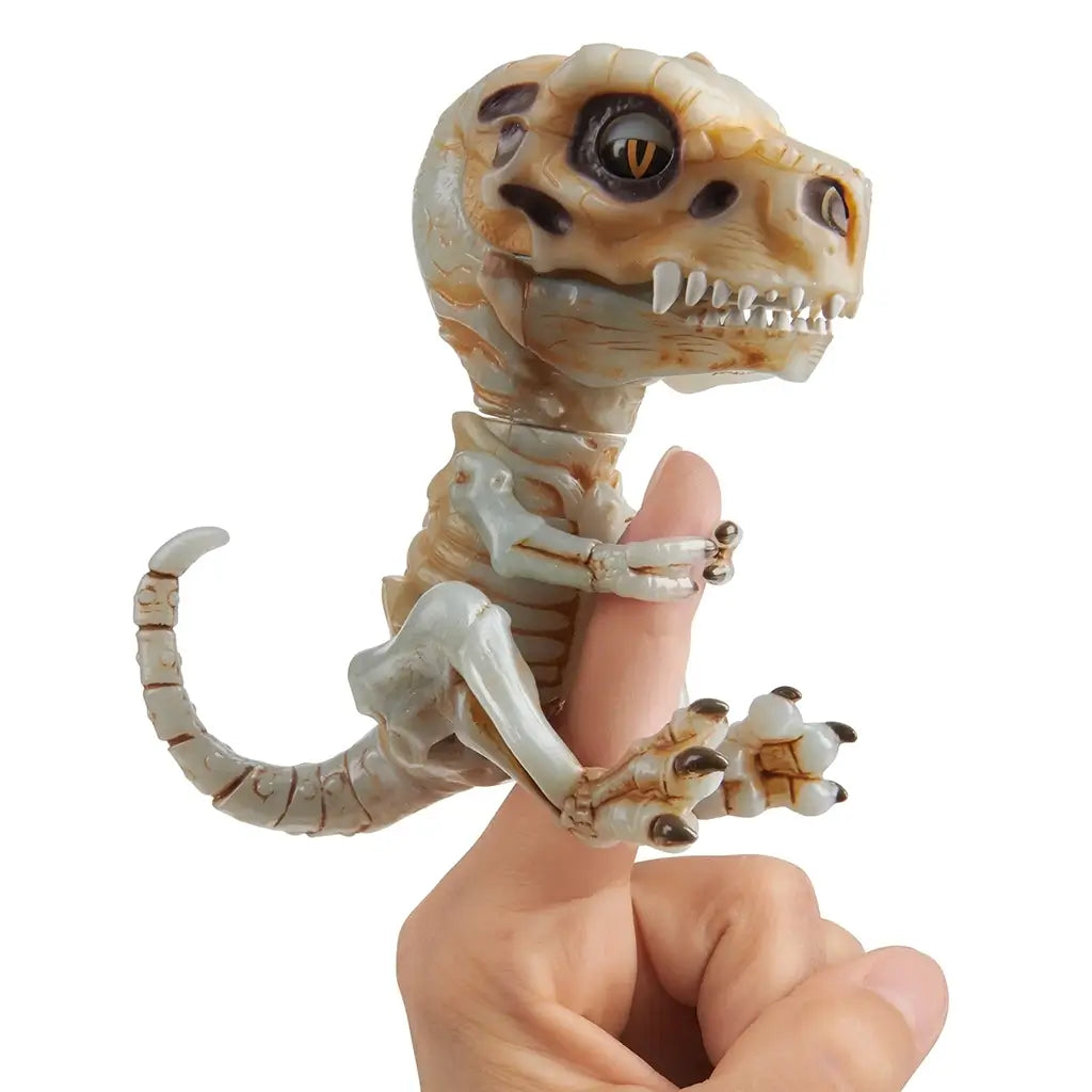 Hand with Untamed Fingerlings Doom Skeleton Dinosaur clinging to a finger, showing its realistic bone design, sharp claws, and bright orange eyes that move when activated.